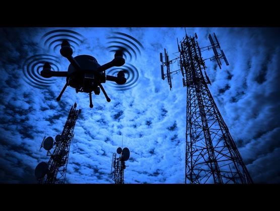 Drone flying near communication towers under a cloudy blue sky 