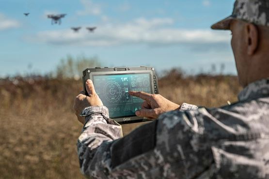 Soldier using a rugged tablet to control drones during an outdoor operation