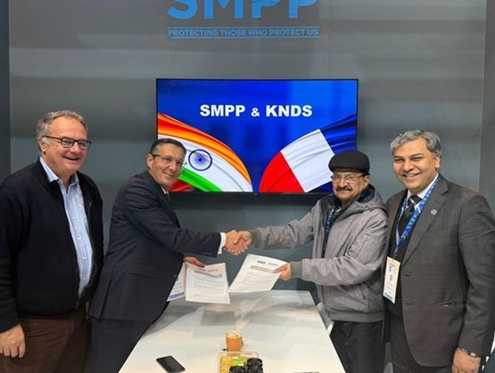 SMPP and KNDS executives formalising a cooperation agreement at Milipol Paris, with Indian and French flags displayed on screen behind them.