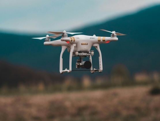 Surveillance drone equipped with a camera flying over a rural landscape