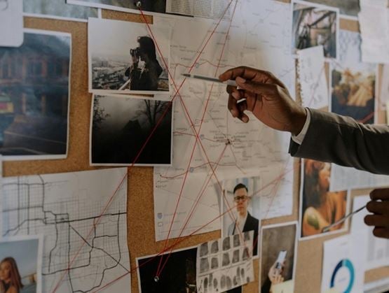 Investigator analysing visual evidence on an investigation board with photos, maps and linked data