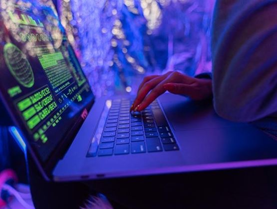 Analyste en cybersécurité tapant sur un ordinateur portable affichant des données et des interfaces de surveillance des menaces.