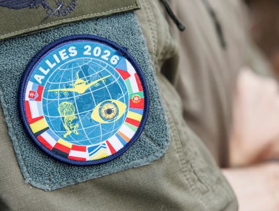 Gros plan sur un écusson militaire « ALLIES 2026 » cousu sur un uniforme, représentant un globe, un avion et plusieurs drapeaux nationaux symbolisant une coopération internationale.
