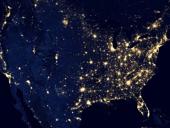 Vue satellite nocturne des États-Unis montrant les lumières des villes et des infrastructures, mettant en évidence la densité urbaine et les réseaux de population.
