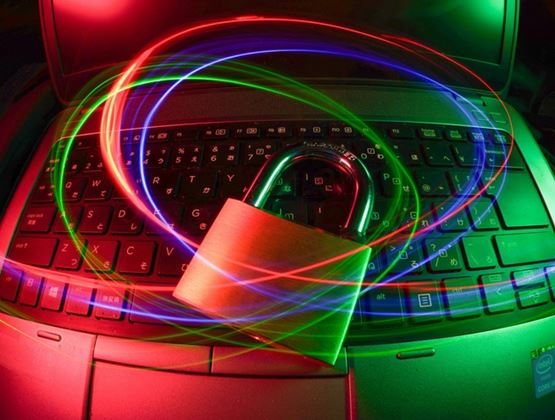 Padlock placed on a laptop keyboard, surrounded by colorful light trails, symbolizing cybersecurity.