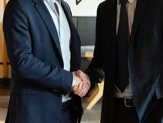 Two people in suits shaking hands during a business meeting.