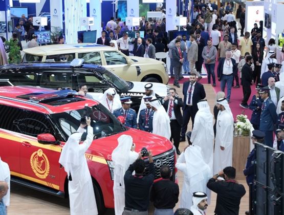 Visitors and security representatives gather around emergency and security vehicles at Milipol Qatar.
