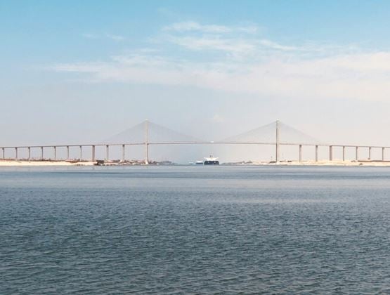 Long bridge crossing calm waters under a clear sky.