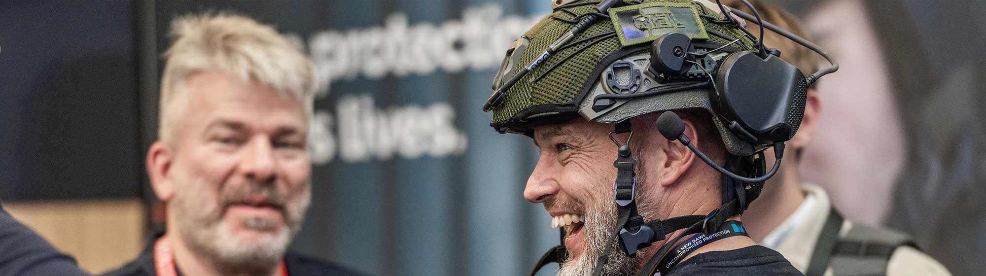 A man wearing a helmet laughs with other exhibitors