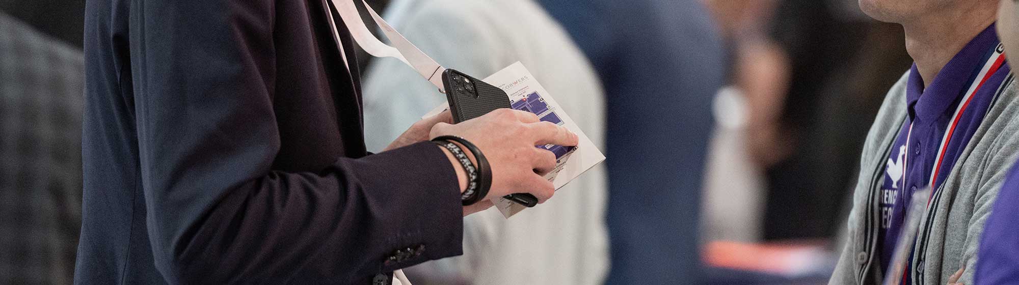 Man asks an exhibitor for information, showing the map of his badge