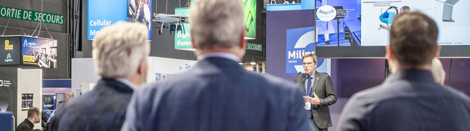 3 men standing to listen an exhibitor's intervention on the innovation stage