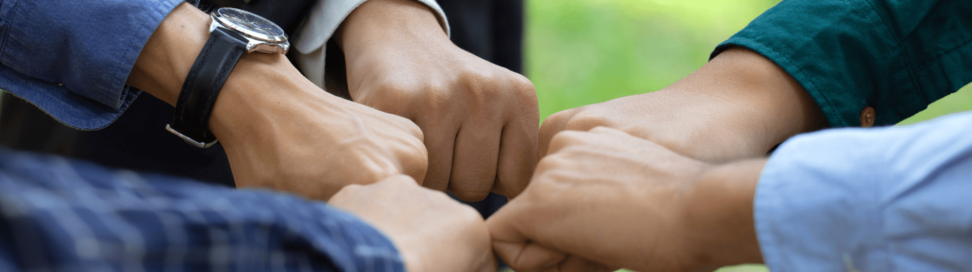 Close-up of several hands forming a circle of fist bumps, symbolizing unity and teamwork