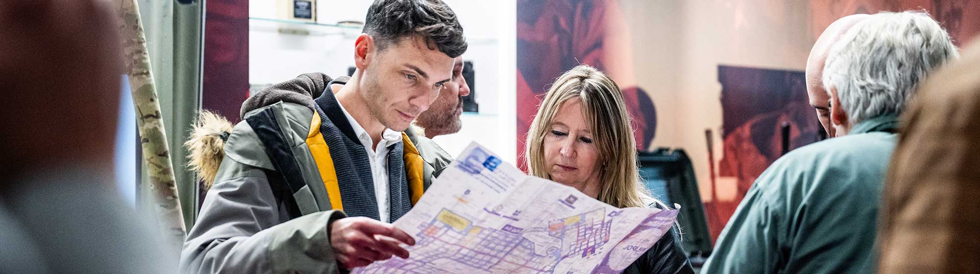 Un homme et une femme debout parmi d'autres visiteurs tenant un plan du salon Milipol Paris
