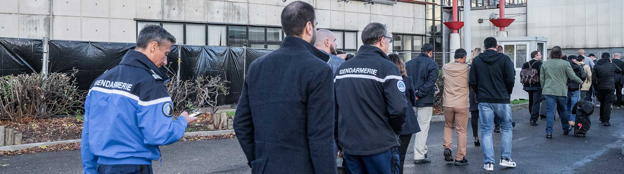 Des personnes marchent à l'extérieur pour accéder à l'événement de Milipol Paris. On voit également une bannière portant la mention "homeland security and safety event" (événement sur la sécurité intérieure).