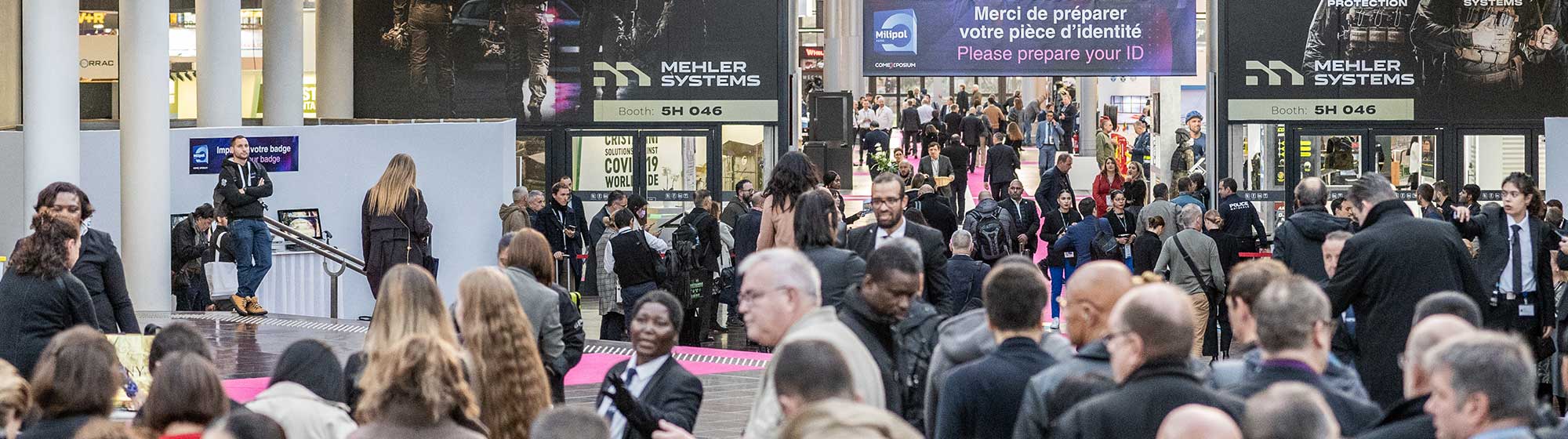 foule de visiteurs à l'entrée du salon milipol paris, une bannière de bienvenue en signalétique aérienne