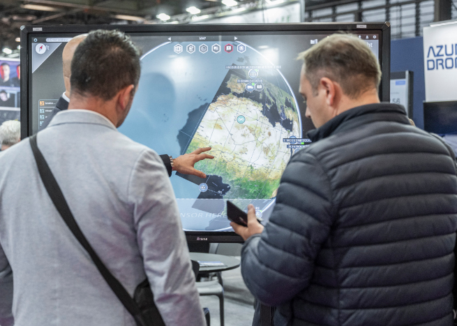 Visiteurs devant un écran sur le stand d'un exposant Milipol Paris