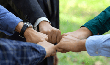 Gros plan de plusieurs mains formant un cercle de poings entrelacés en signe d’unité et de collaboration