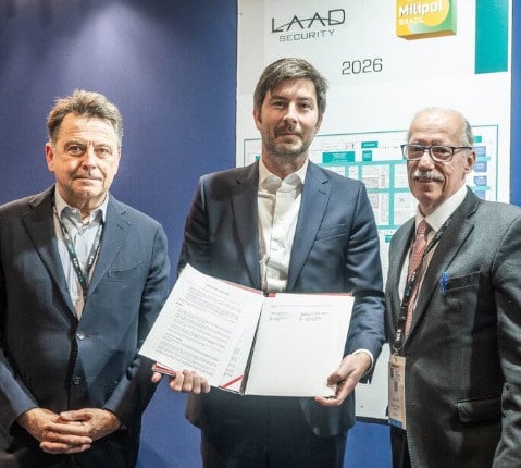 Chairmen of Civipol, Comexposium & LAAD Security in suits posing in front of a Milipol Brazil 2026 poster, holding a signed partnership agreement