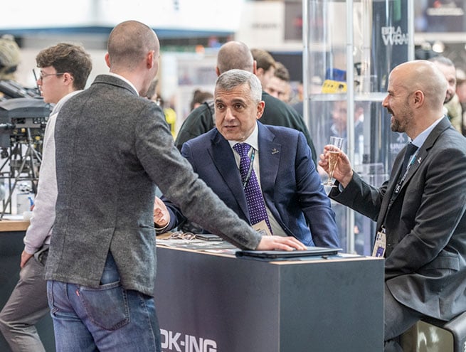 3 exposants discutant business et buvant du champagne sur un stand