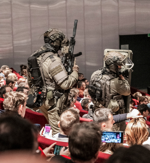 Intervention simulée du GIGN dans un auditorium rempli de spectateurs lors du salon Milipol Paris, avec deux agents armés en tenue tactique