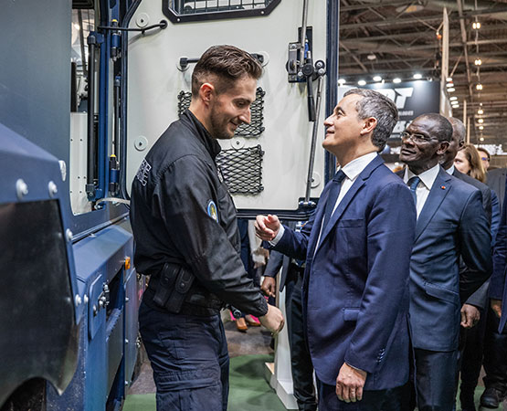Gérard Darmanin en conversation avec un gendarme sur son stand devant un camion de la gendarmerie nationale