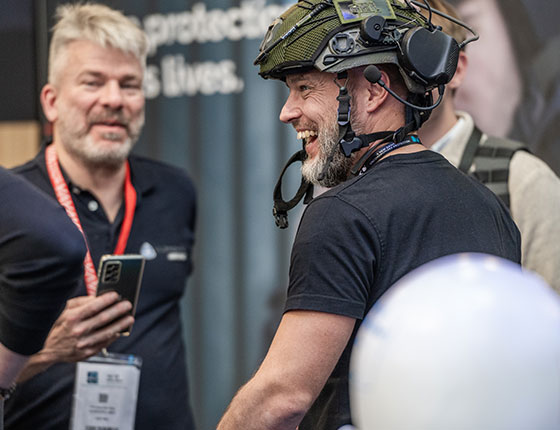 A man wearing a helmet laughs with other exhibitors