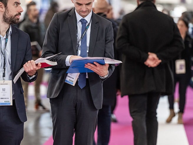 2 hommes qui marchent, consultent le plan du salon