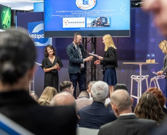 Lauréate d'un Milipol Innovation Awards sur scène de l'Innovation Stage, recevant un trophée des mains des organisateurs devant un parterre de visiteurs durant Milipol Paris