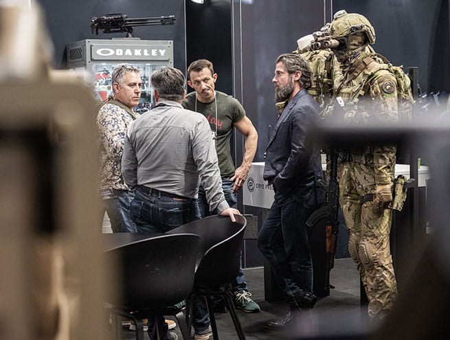 3 hommes discutant sur le stand d'Oakley entourés d'uniformes militaires