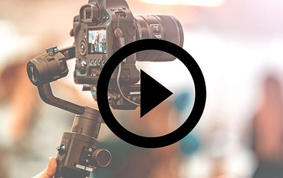 hand holding a video camera with a play symbol over the image